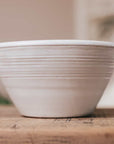 White ceramic bowl with ridges on wooden console. 