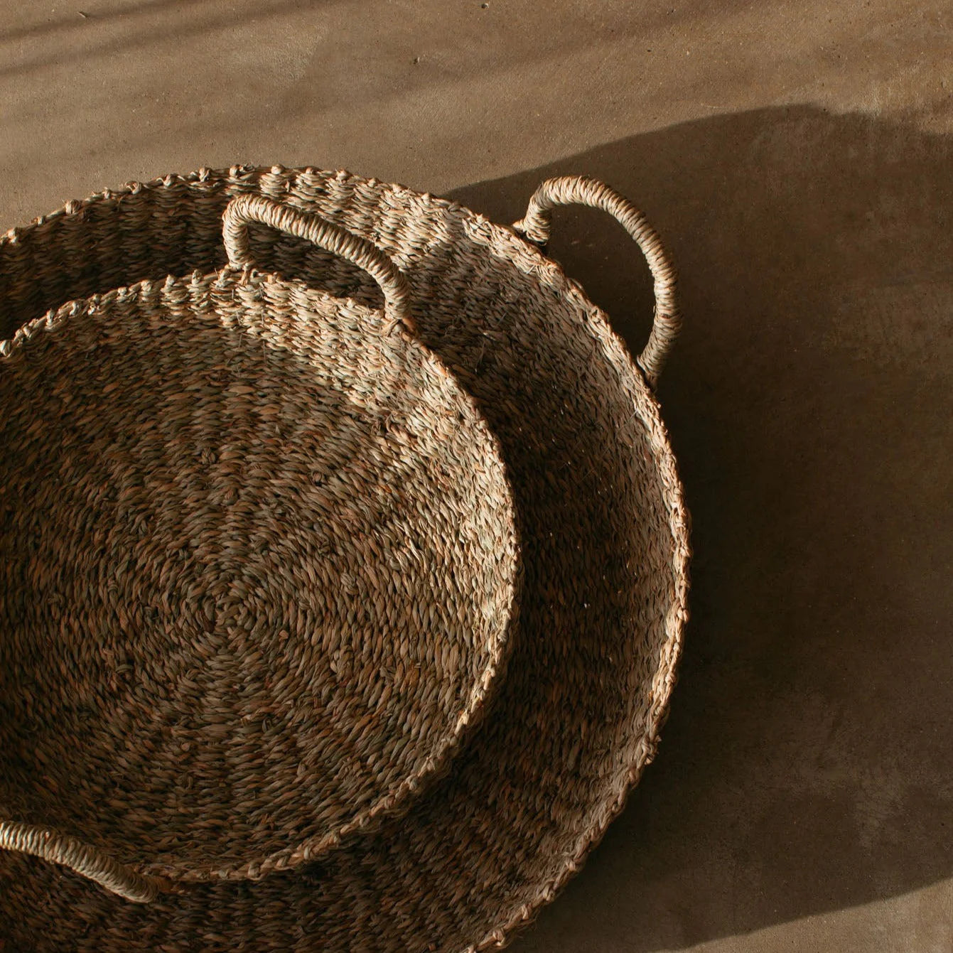 A birds-eye view of the Evelyn Seagrass Baskets on a concrete floor. 