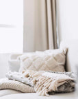 Pile of neutral coloured blankets on sofa.