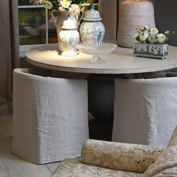 Natural linen dining chair under round farmhouse table.