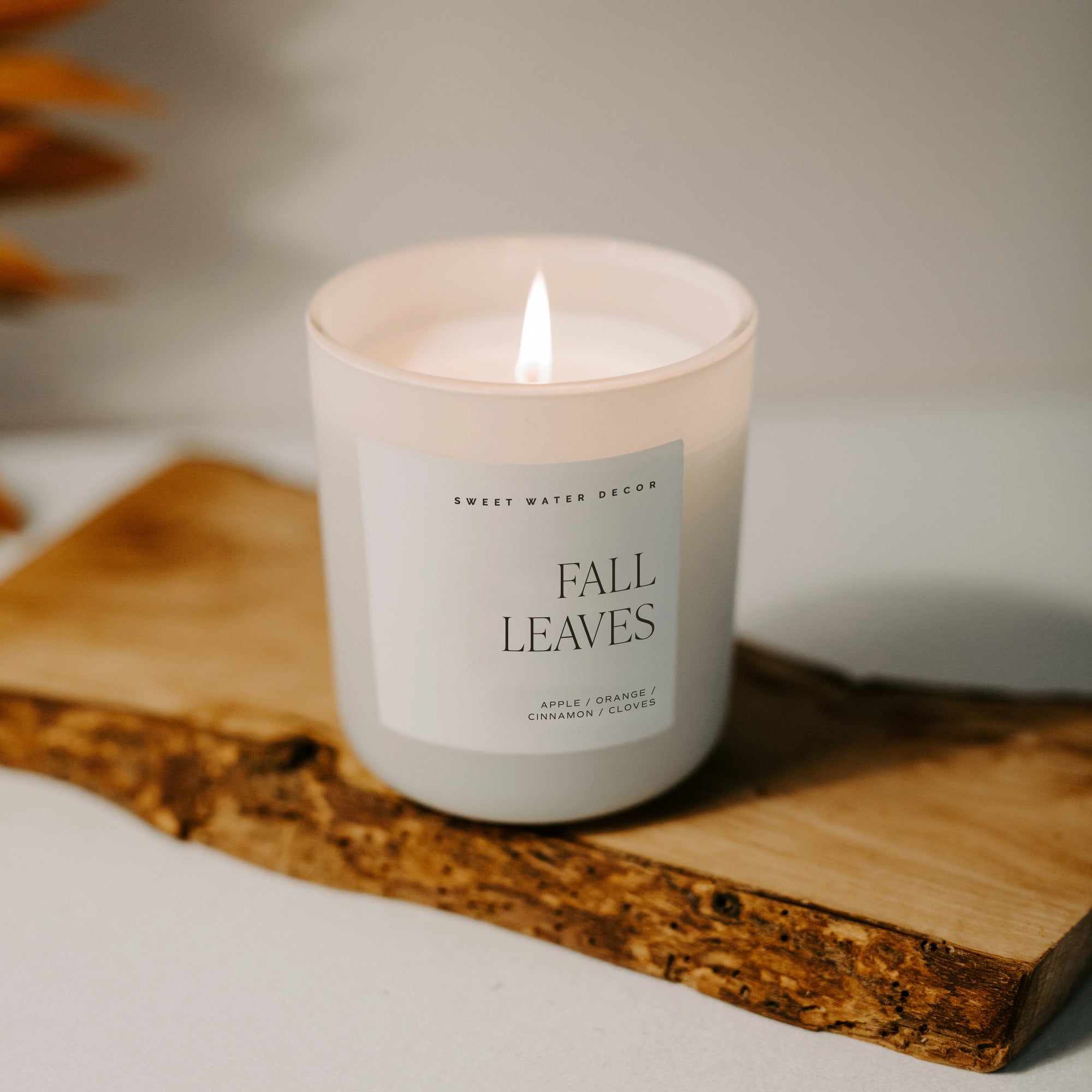 White soy candle on wooden plank, lit.