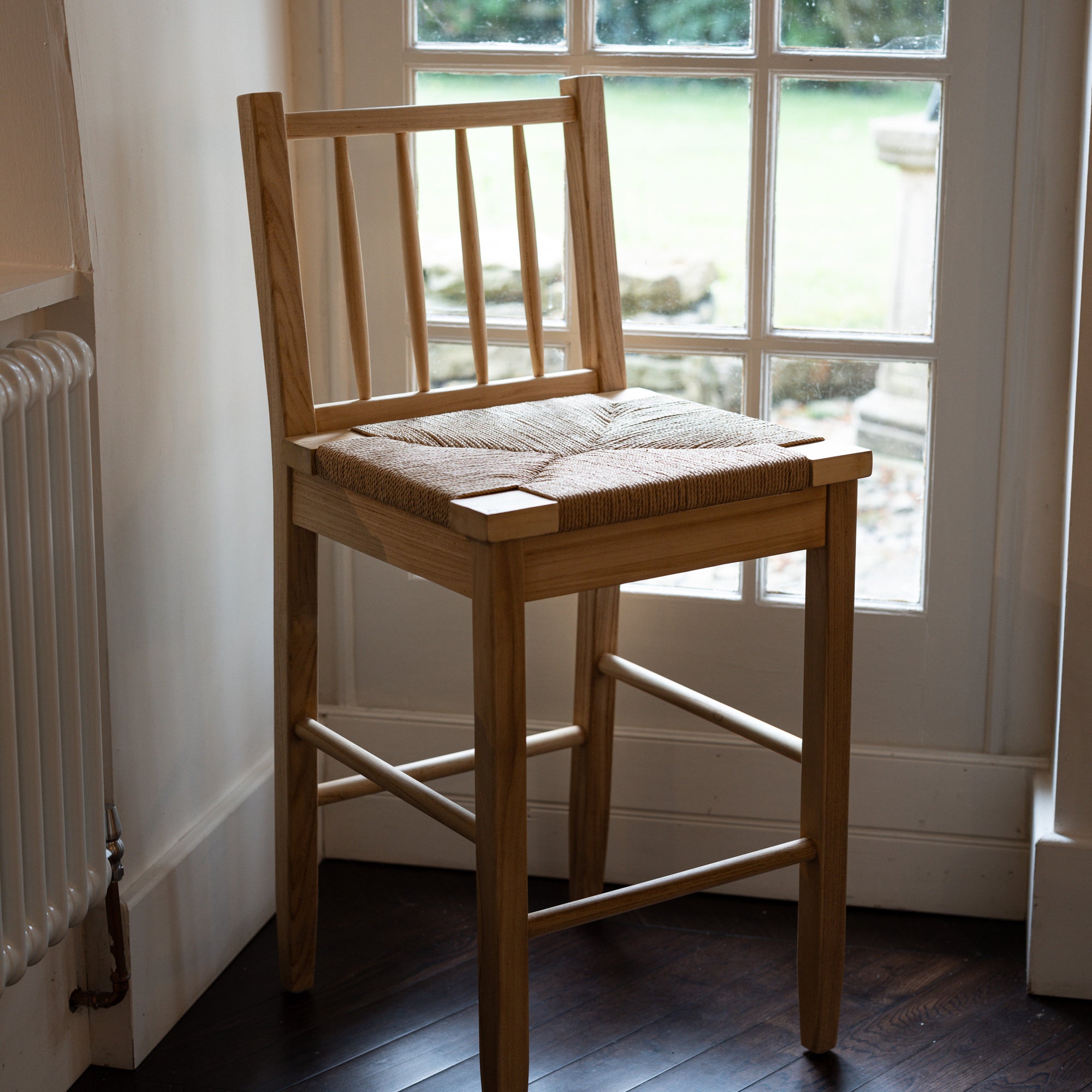 Farmhouse Rattan Bar Stool in kitchen with dark wood floor by the window.