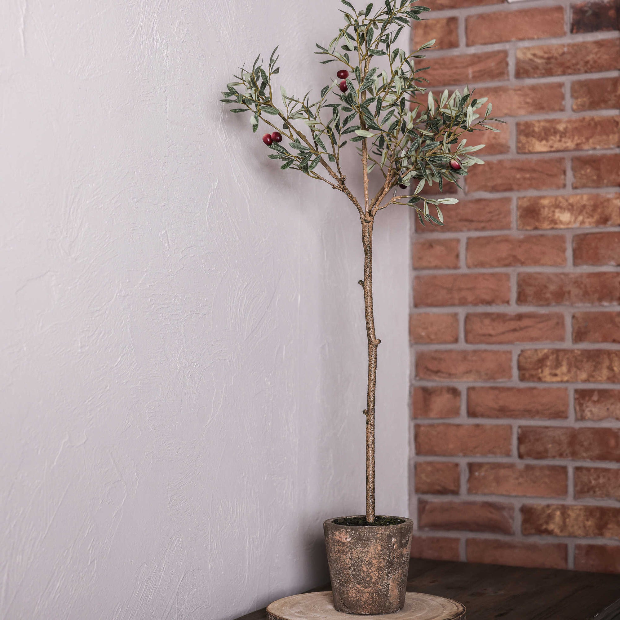 Faux olive tree in clay pot in corner of room.