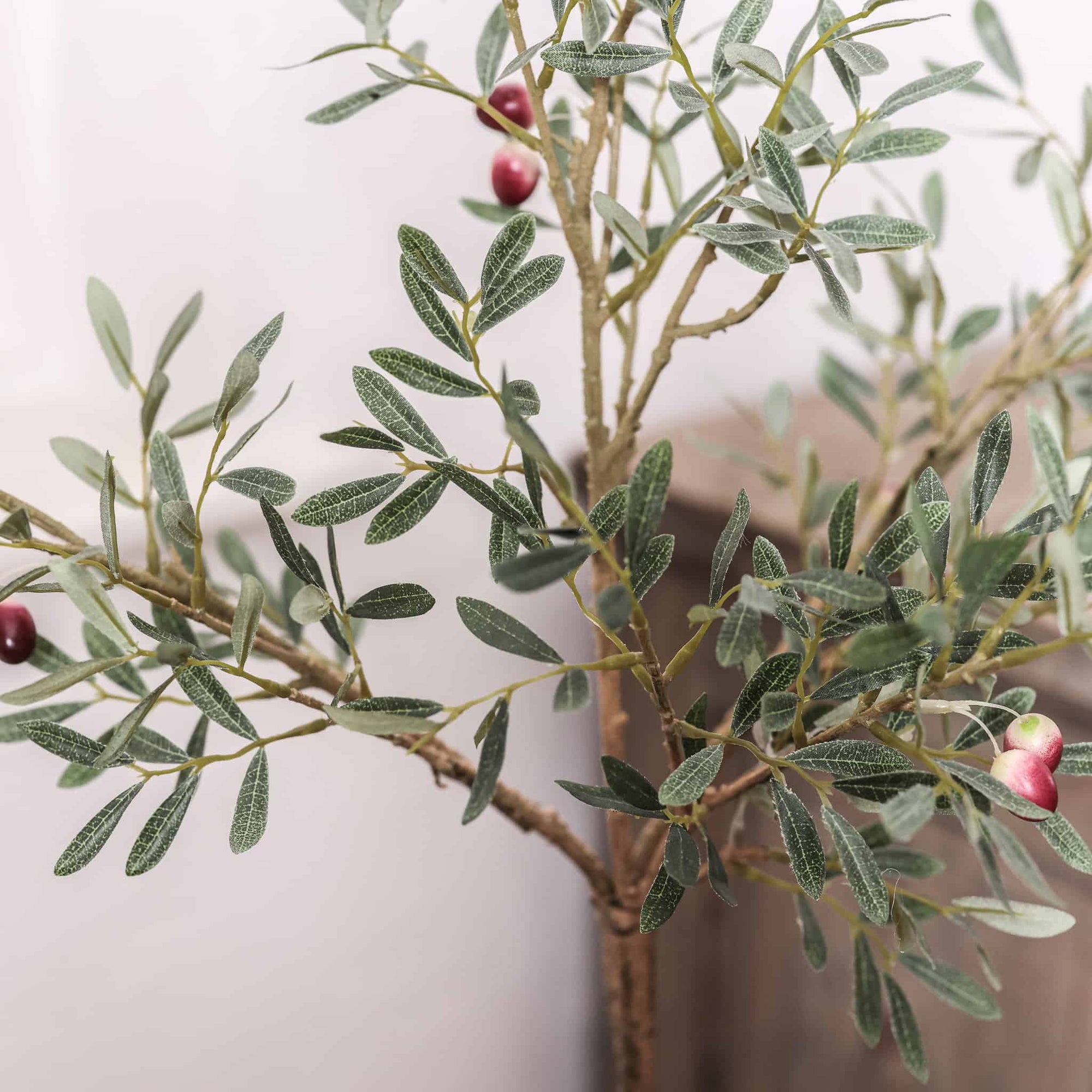 Close up of artificial leaves and olives on faux olive tree. 