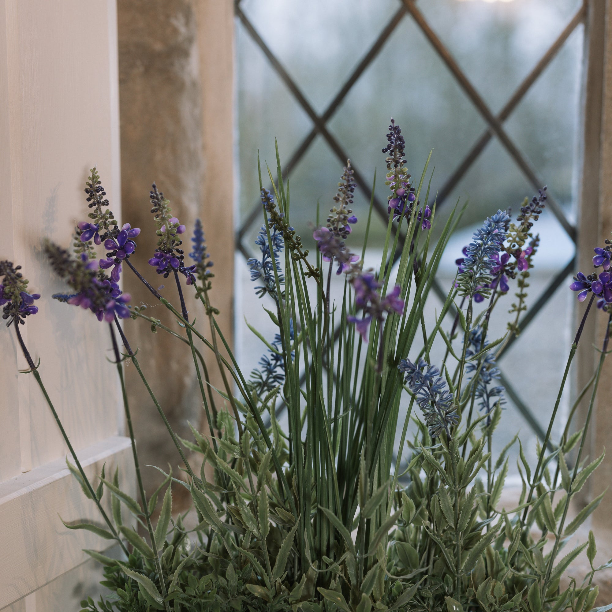 Detailed shot of Faux lavender plant in pot on stone windowsill. 