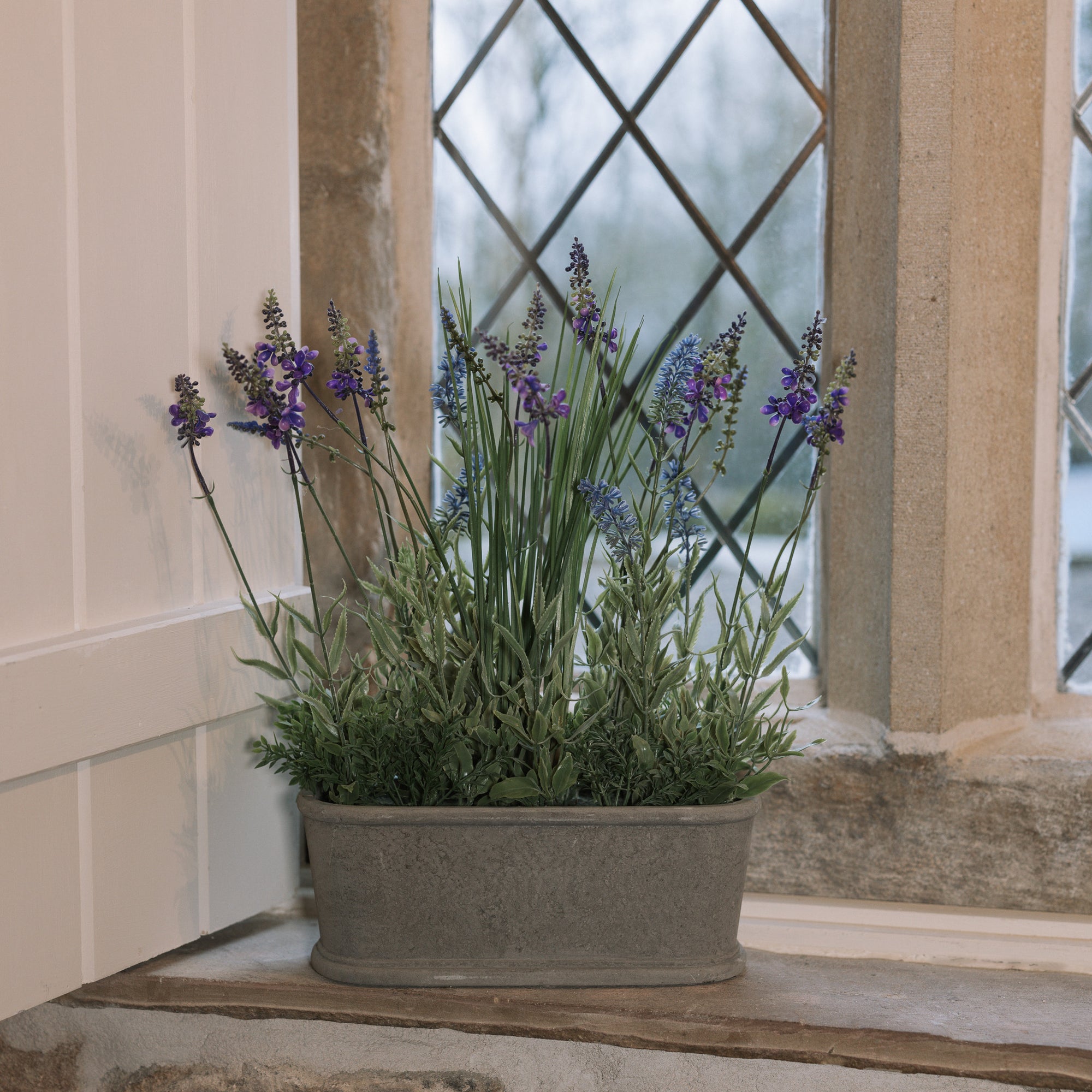 Faux lavender plant in pot on stone windowsill. 