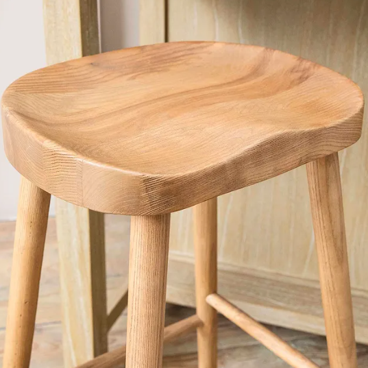 Close up of curved seat on backless wooden bar stool. 