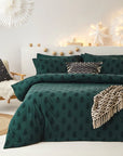 Green Christmas bedding with trees on double bed with decorations and patterned throws and cushions.