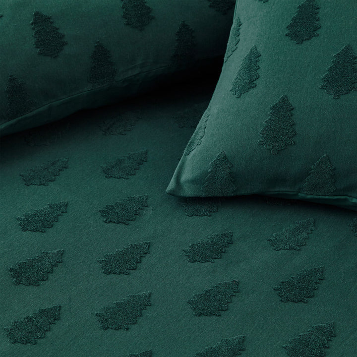 Close up of green Christmas bedding with trees, with duvet and cushions.