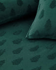 Close up of green Christmas bedding with trees, with duvet and cushions.