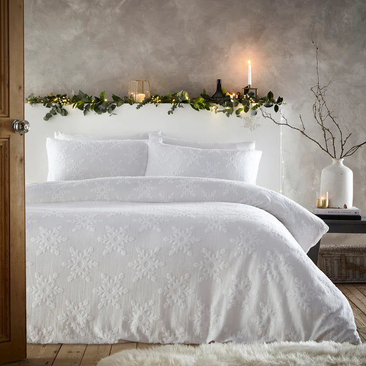 White Christmas bedding with snowflakes, on double bed with wreath and candle on bade frame.