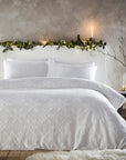 White Christmas bedding with snowflakes, on double bed with wreath and candle on bade frame.