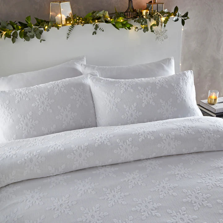 Close up of white Christmas bedding with snowflakes on double bed.