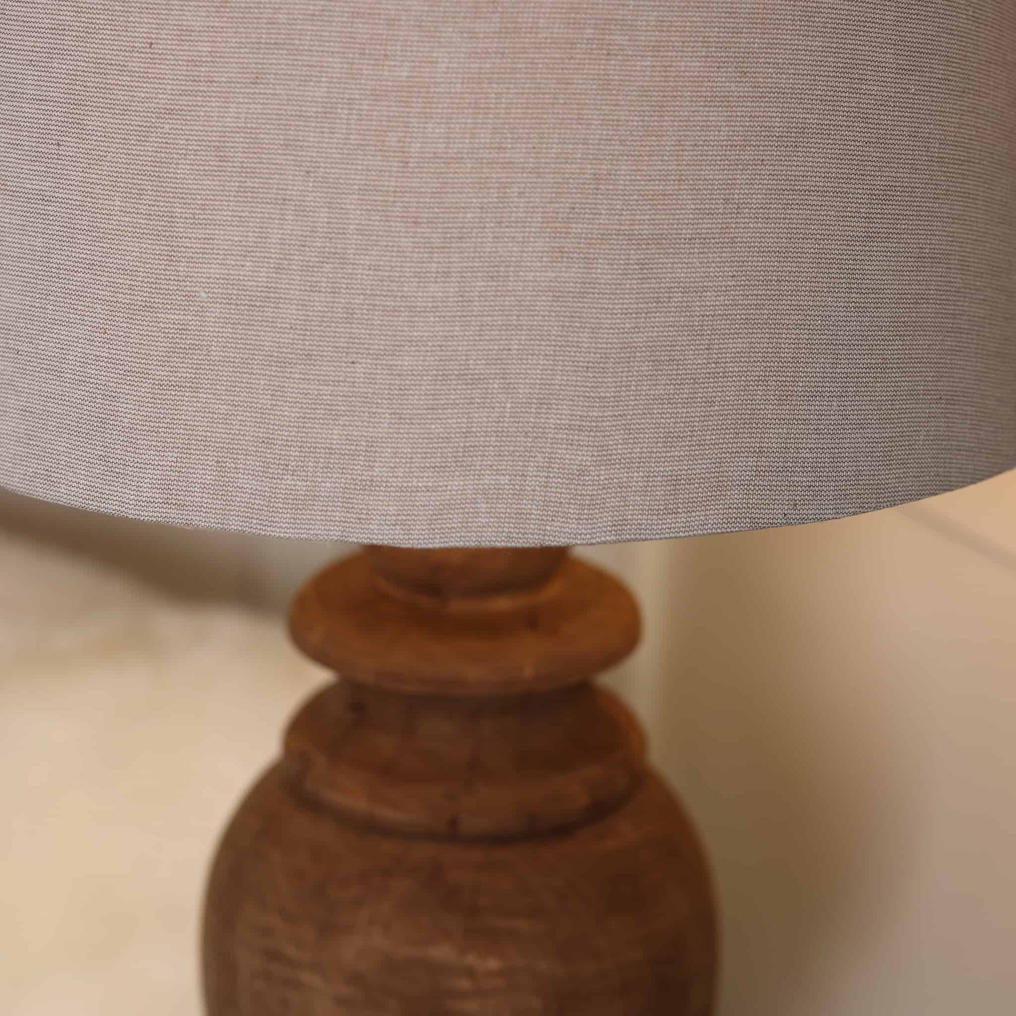 Close up of neutral linen lamp shade with wooden base. 