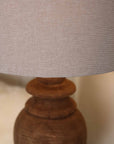 Close up of neutral linen lamp shade with wooden base. 