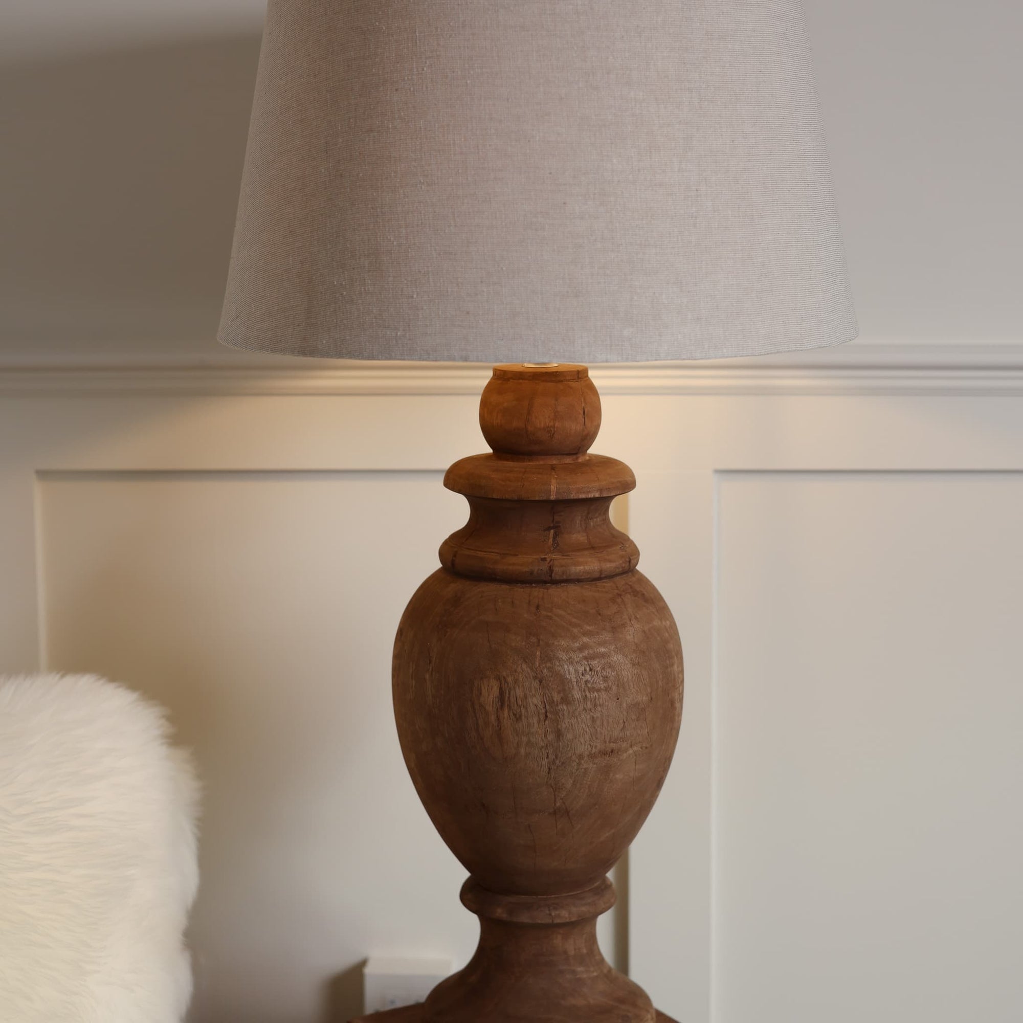Wooden lamp lit close up with linen lamp shade. 
