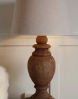 Wooden lamp lit close up with linen lamp shade. 