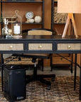 Black and rattan wooden desk with drawers in office.