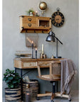 Wooden desk with drawers with rattan front and black legs with office chair and blanket.