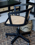 Black rattan office chair on rug with matching table.