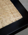 Close up of rattan seat on black office chair.