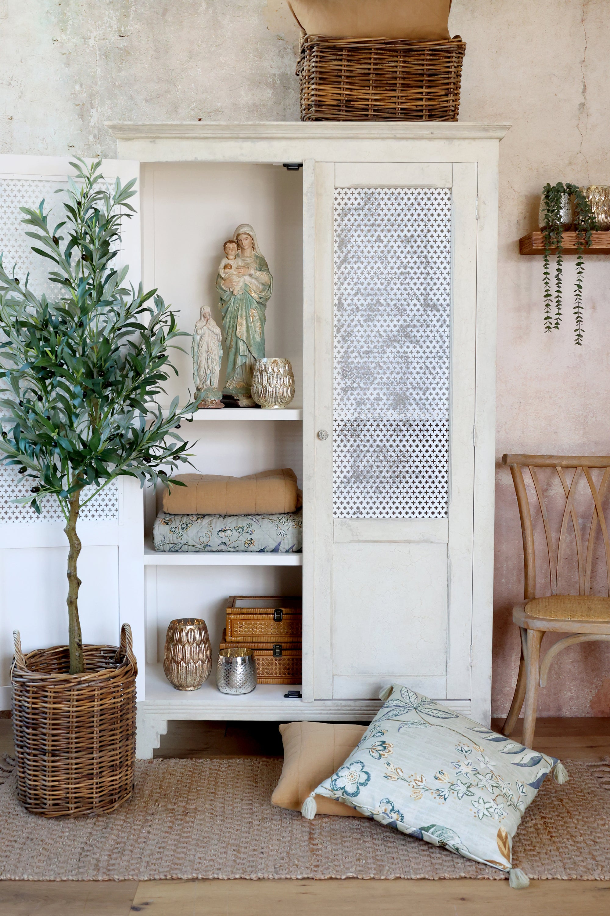 Antique cream linen closet with mesh doors, open with textiles inside.