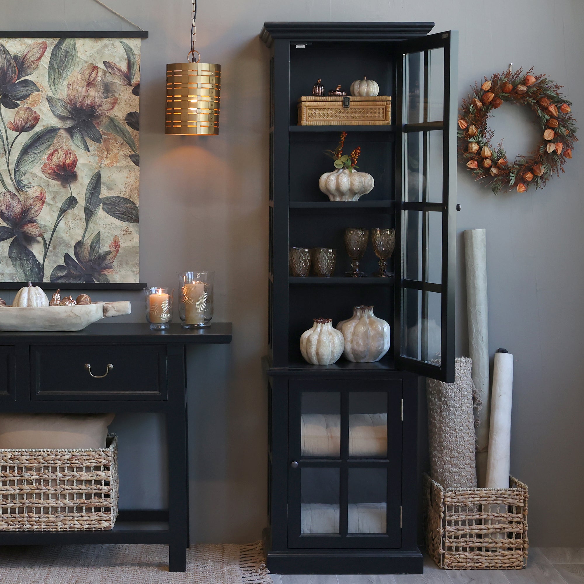 Black display cabinet with glass doors open and autumnal decor.