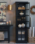 Black display cabinet with glass doors open and autumnal decor.