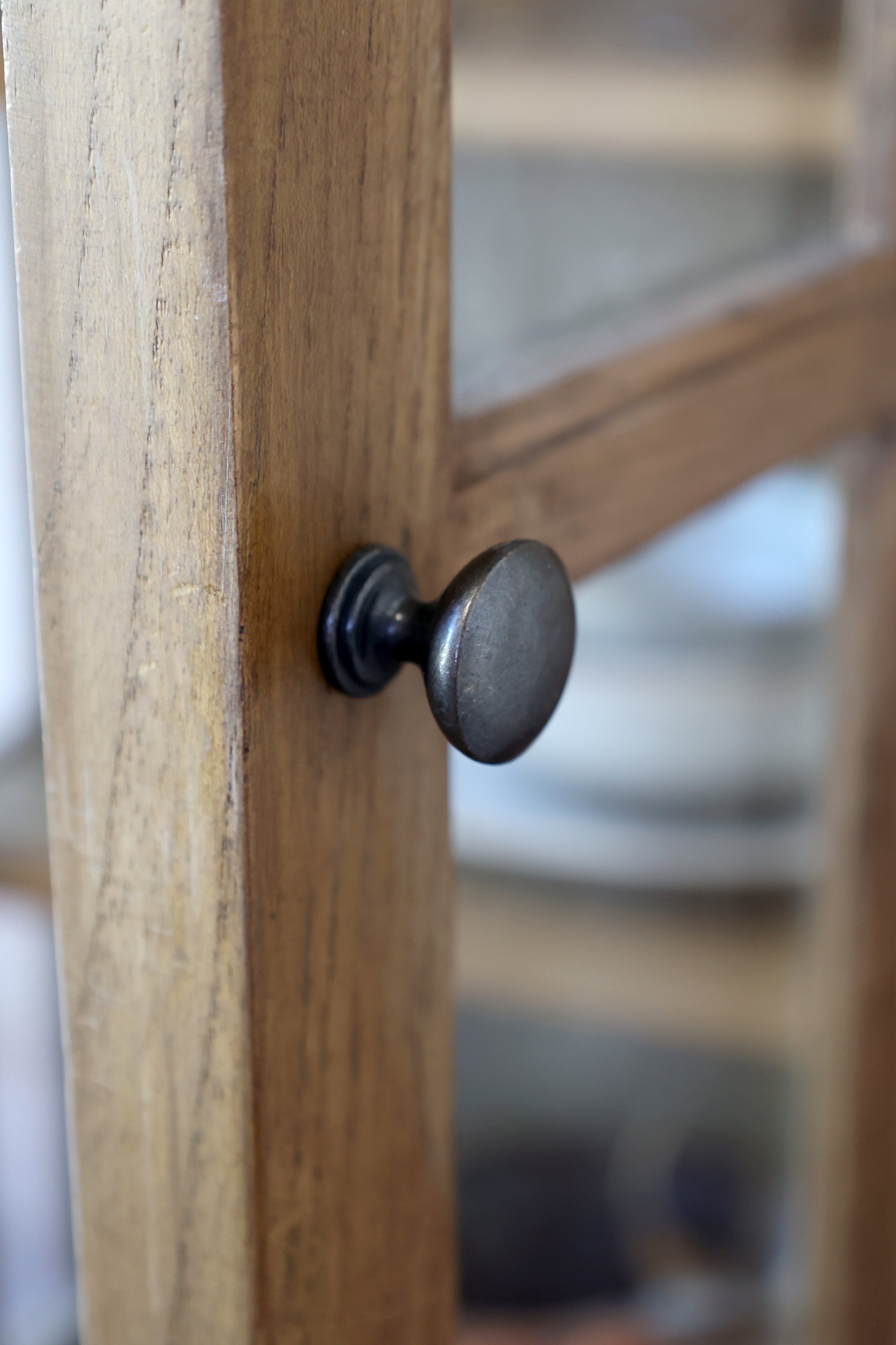 Close up of door knob on natural wood display cabinet.