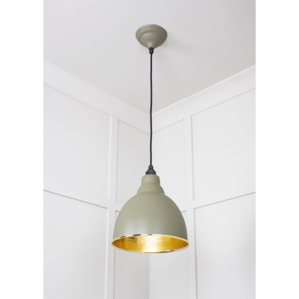 Hammered brass pendant light with tump finish, attached to ceiling and switched on.