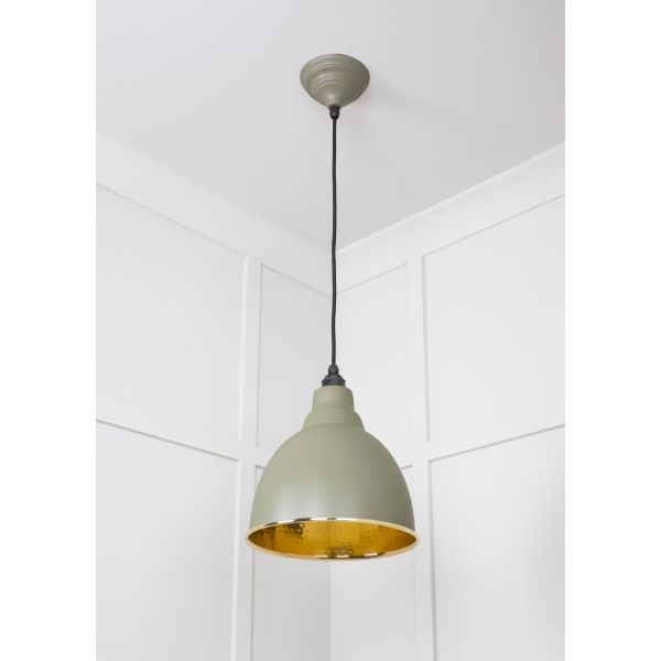 Hammered brass pendant light with tump finish, attached to ceiling and switched off.