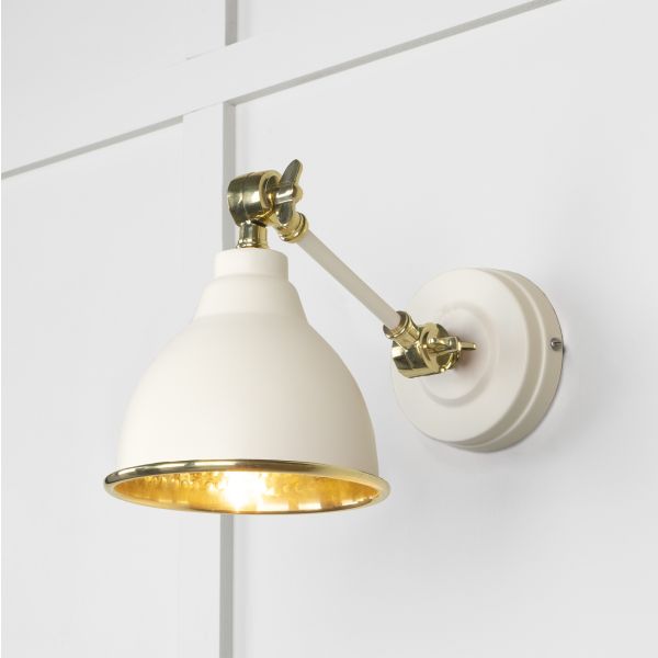 Teasal and brass hammered wall light, attached to white wall and switched on.