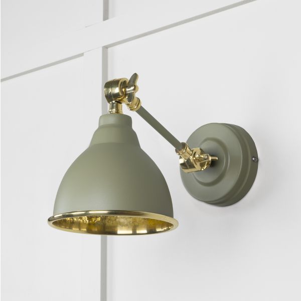 Hammered brass wall light in tump, switched off and attached to white wall.