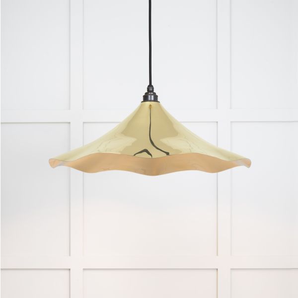 Shade of floral shaped smooth brass pendant light, switched on.