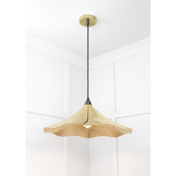 Shade of floral shaped smooth brass pendant light, switched off.