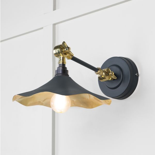 Black and brass floral wall light, attached to wall and switched on.