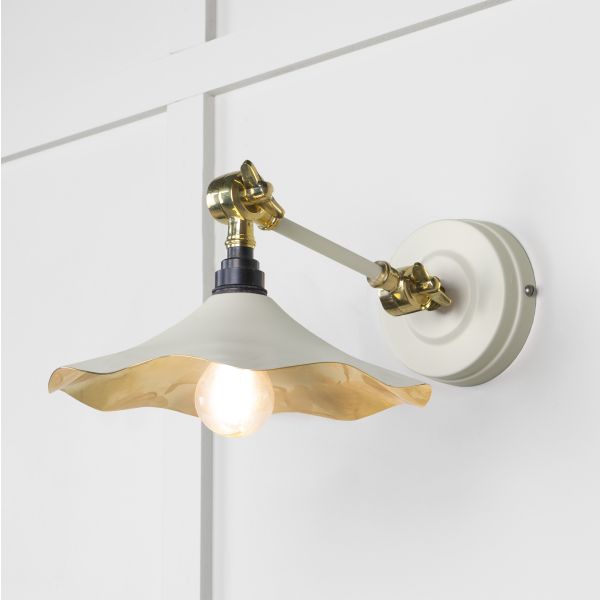 Brass and white floral wall light, attached to wall and switched on.