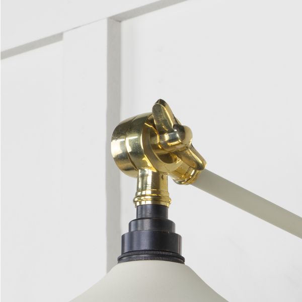 Close up of knuckle on white and brass wall light.