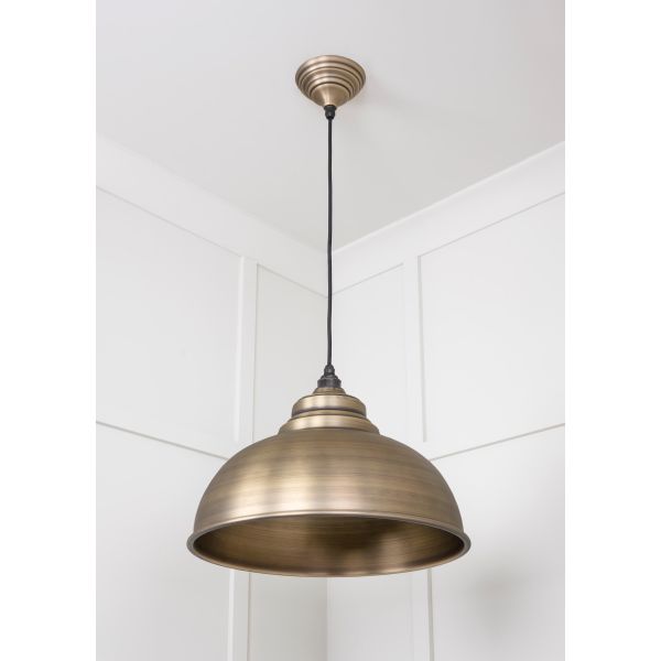 Aged brass pendant light switched off, hanging from ceiling. 