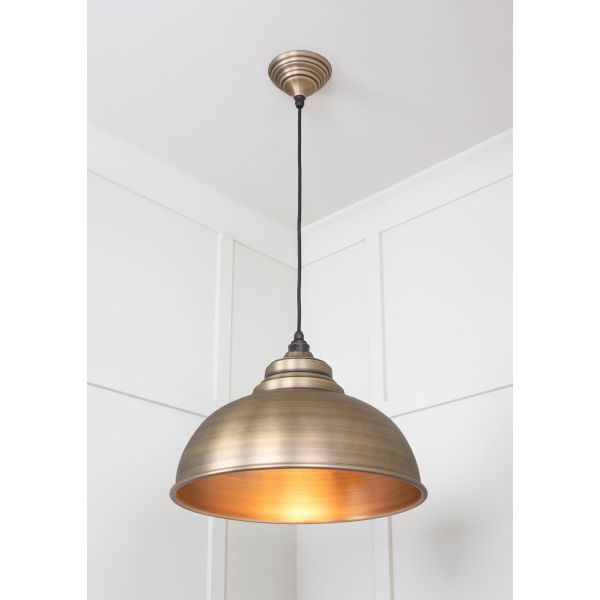 Aged brass pendant light switched on, hanging from ceiling.