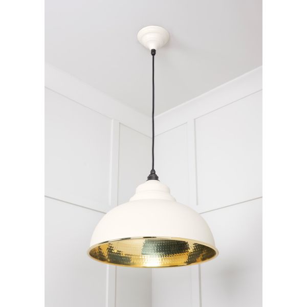 Hammered brass pendant light in teasel, attached to ceiling, switched off.