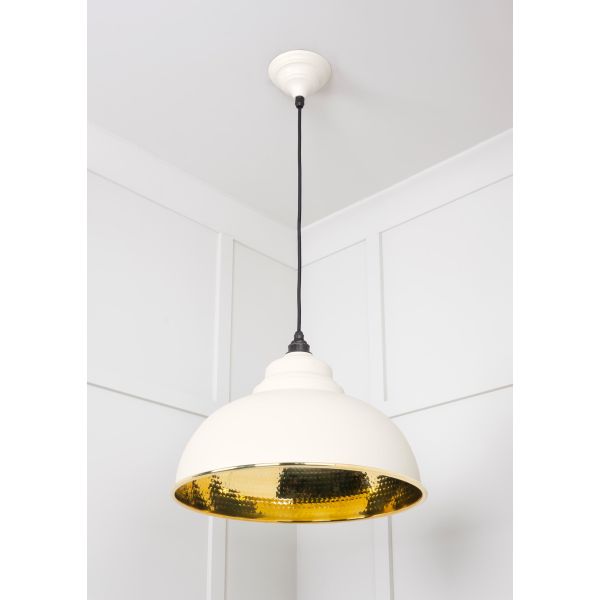 Hammered brass pendant light in teasel, attached to ceiling.