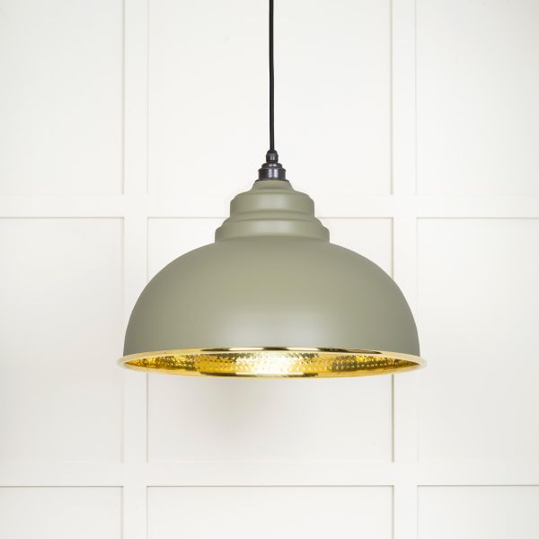 Shade of hammered brass pendant light in green, switched on.