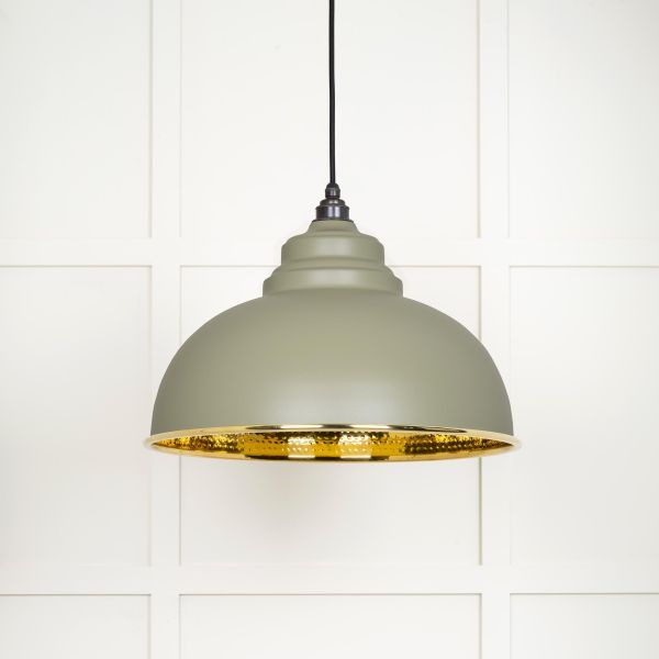 Shade of hammered brass pendant light in green, switched off.