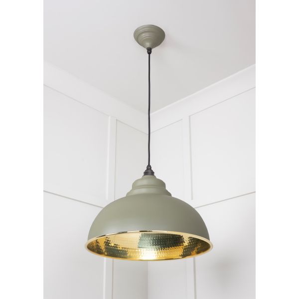 Hammered brass pendant light in green, attached to ceiling.