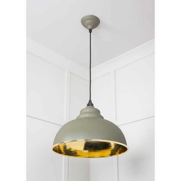 Hammered brass pendant light in green, attached to ceiling.