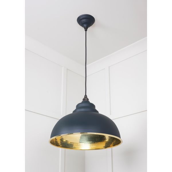 Brass and black pendant light, switched on.