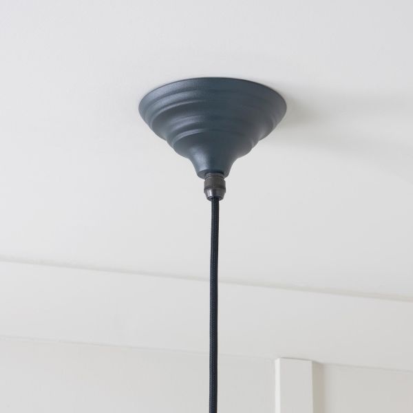 Close up of rose on brass and black pendant light, attached to ceiling.