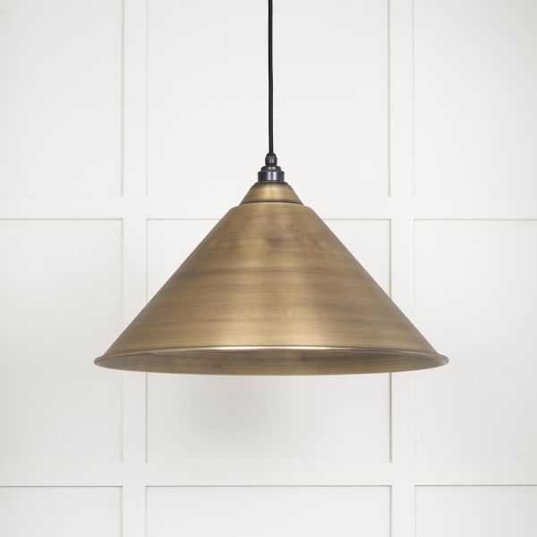 Cone shaped aged brass pendant light shade switched off.