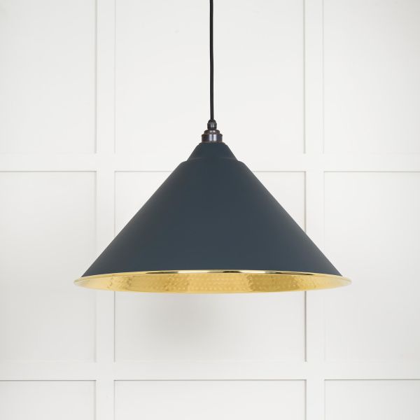 Shade on cone shaped brass and black pendant light, switched off.